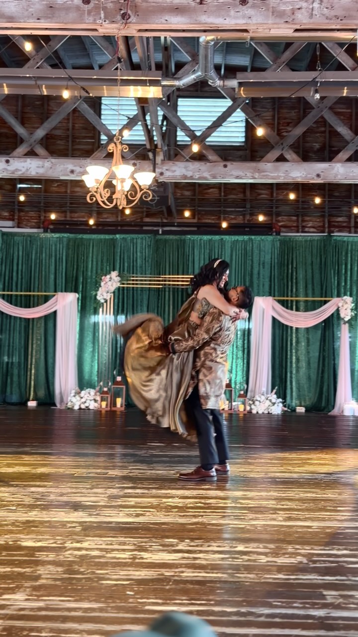 Bride and groom dancing under chandeliers at a barn wedding reception