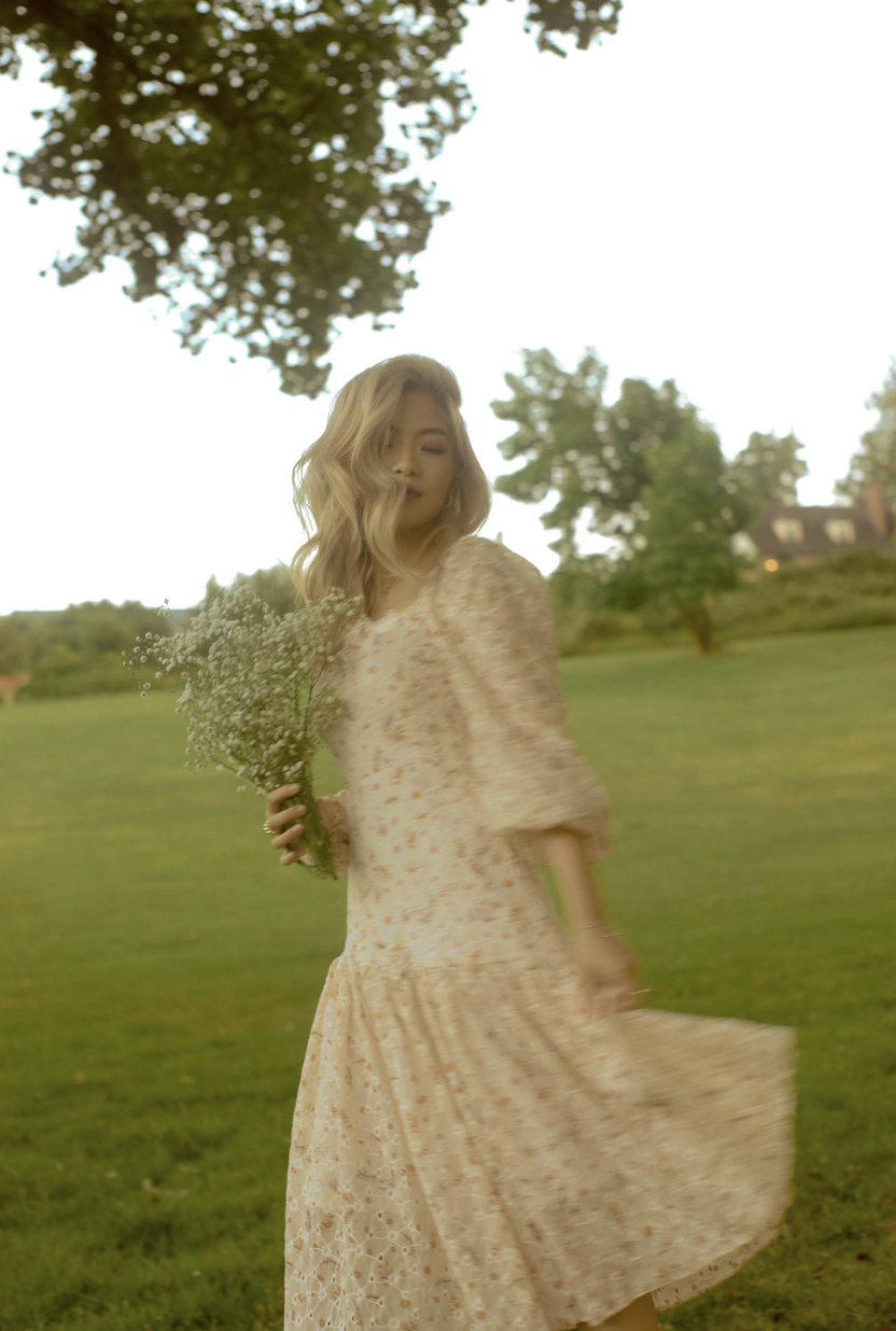 A woman in a floral dress with her skirt moving in the wind