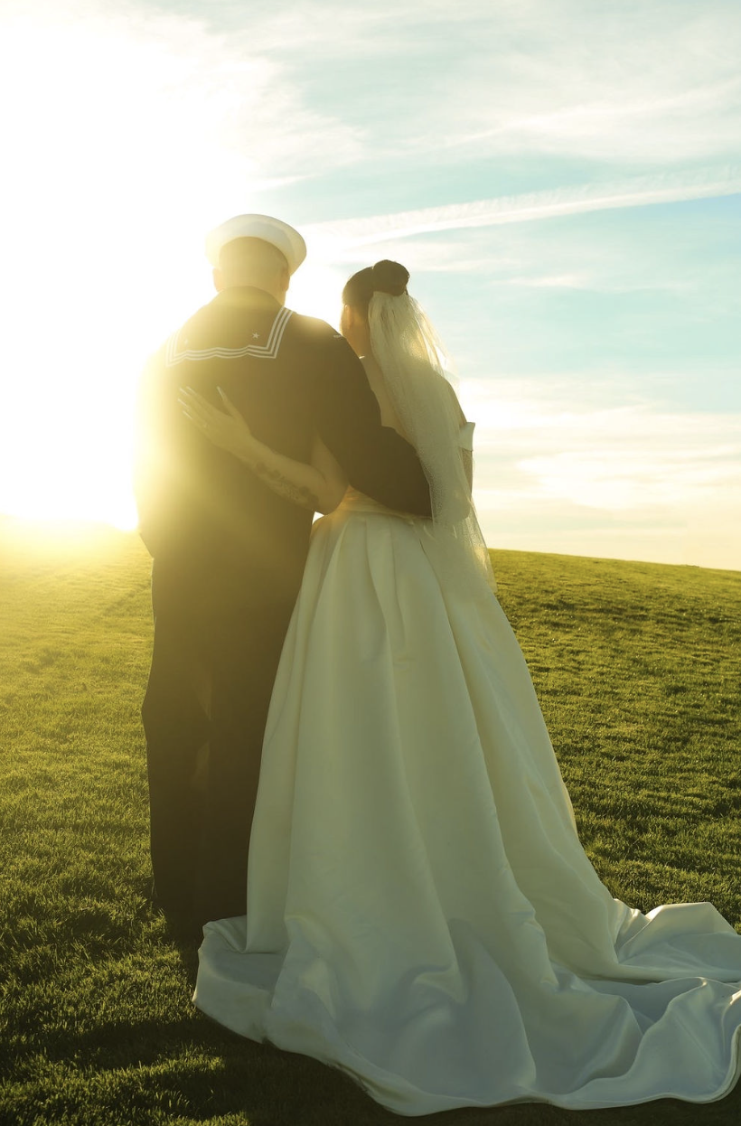 Newlyweds embracing on a hill at sunset