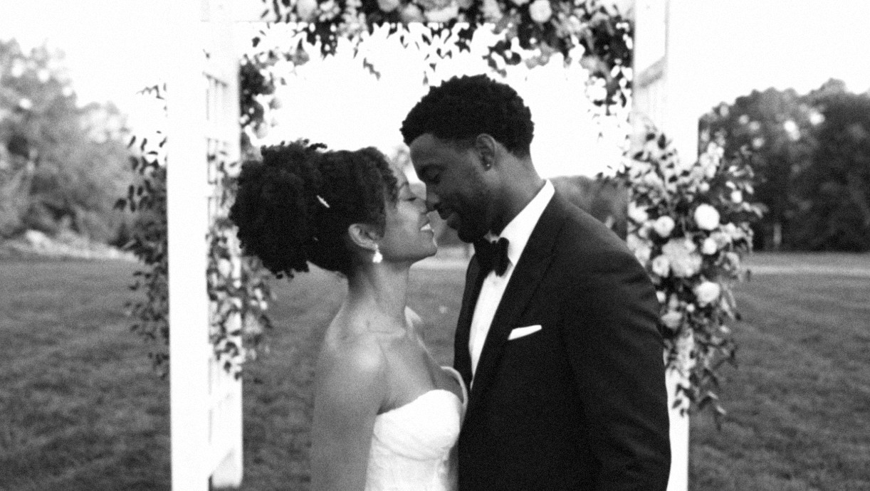 A couple sharing a kiss beneath a floral arch
