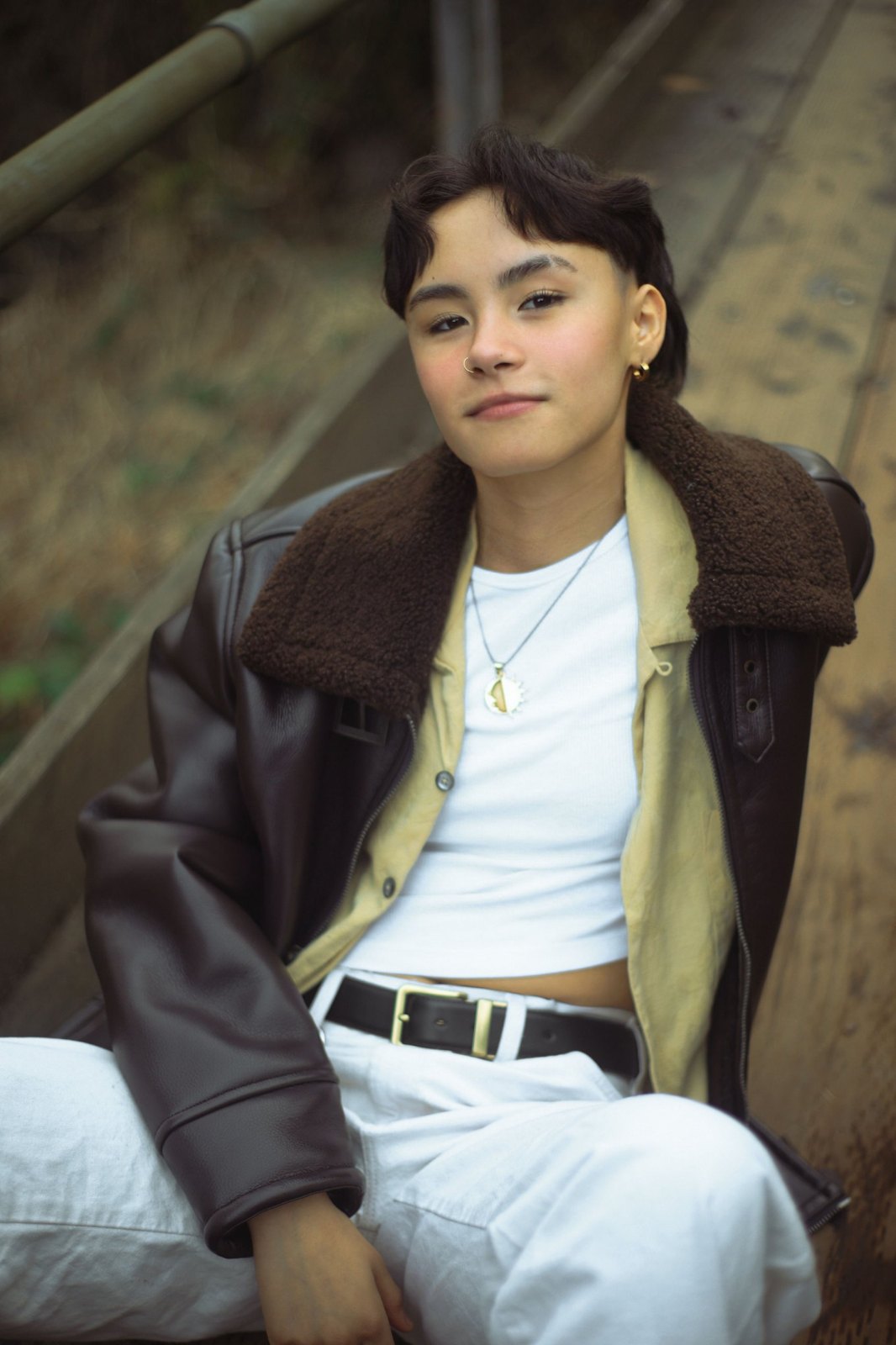 Senior in a leather jacket seated on wooden stairs