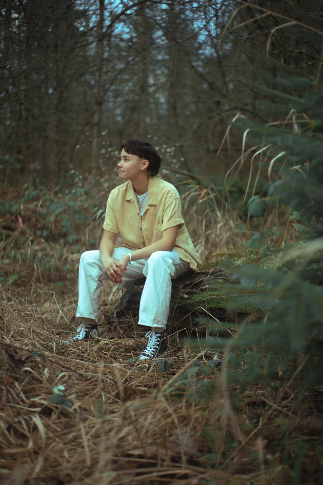 Senior seated on a log in the forest, looking off to the side