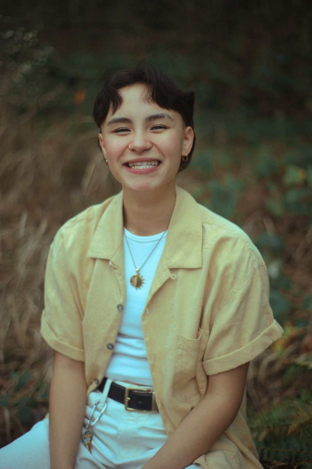 Senior laughing in a yellow shirt and sun pendant