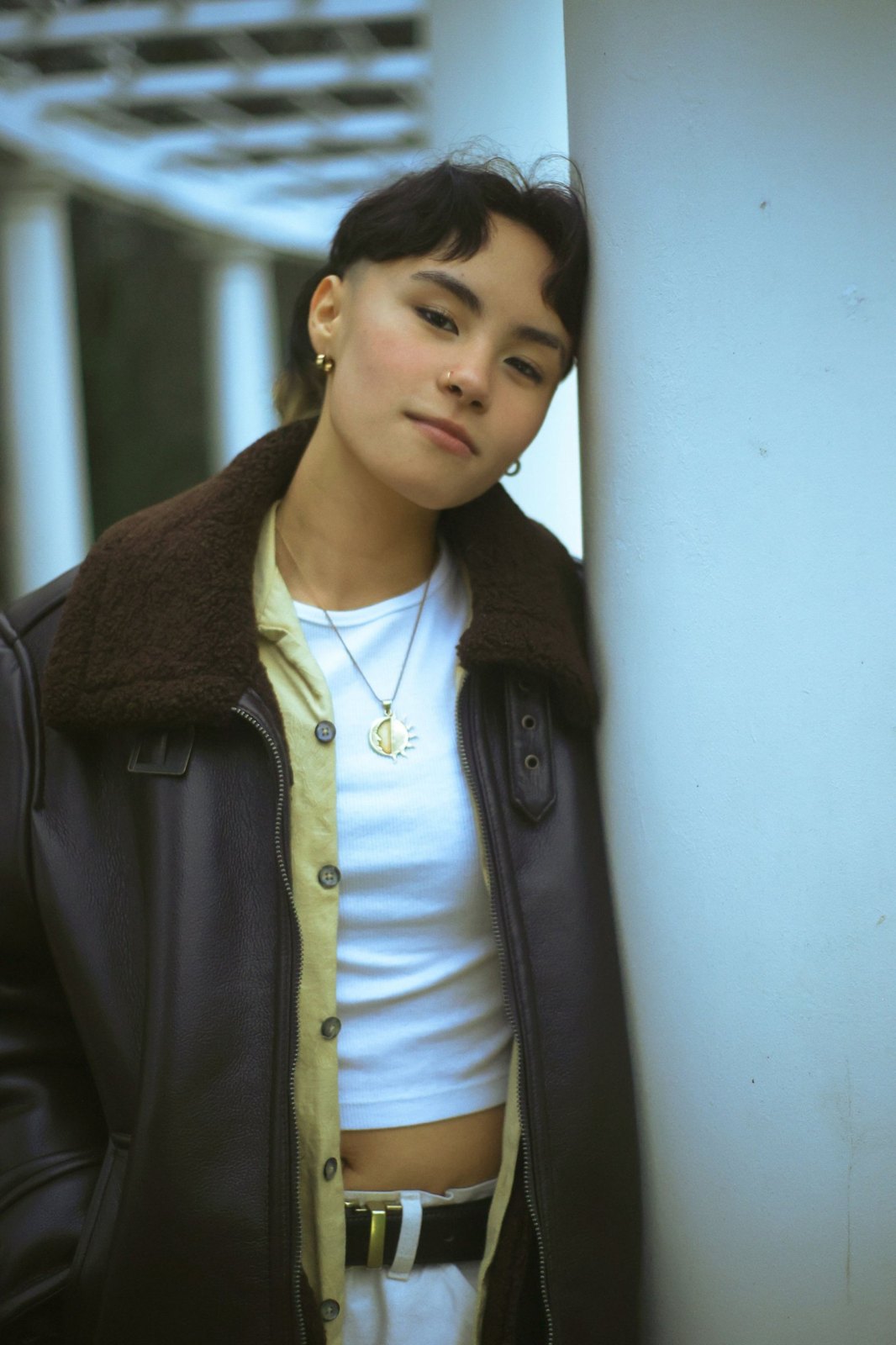 Senior leaning against a white column in a leather jacket