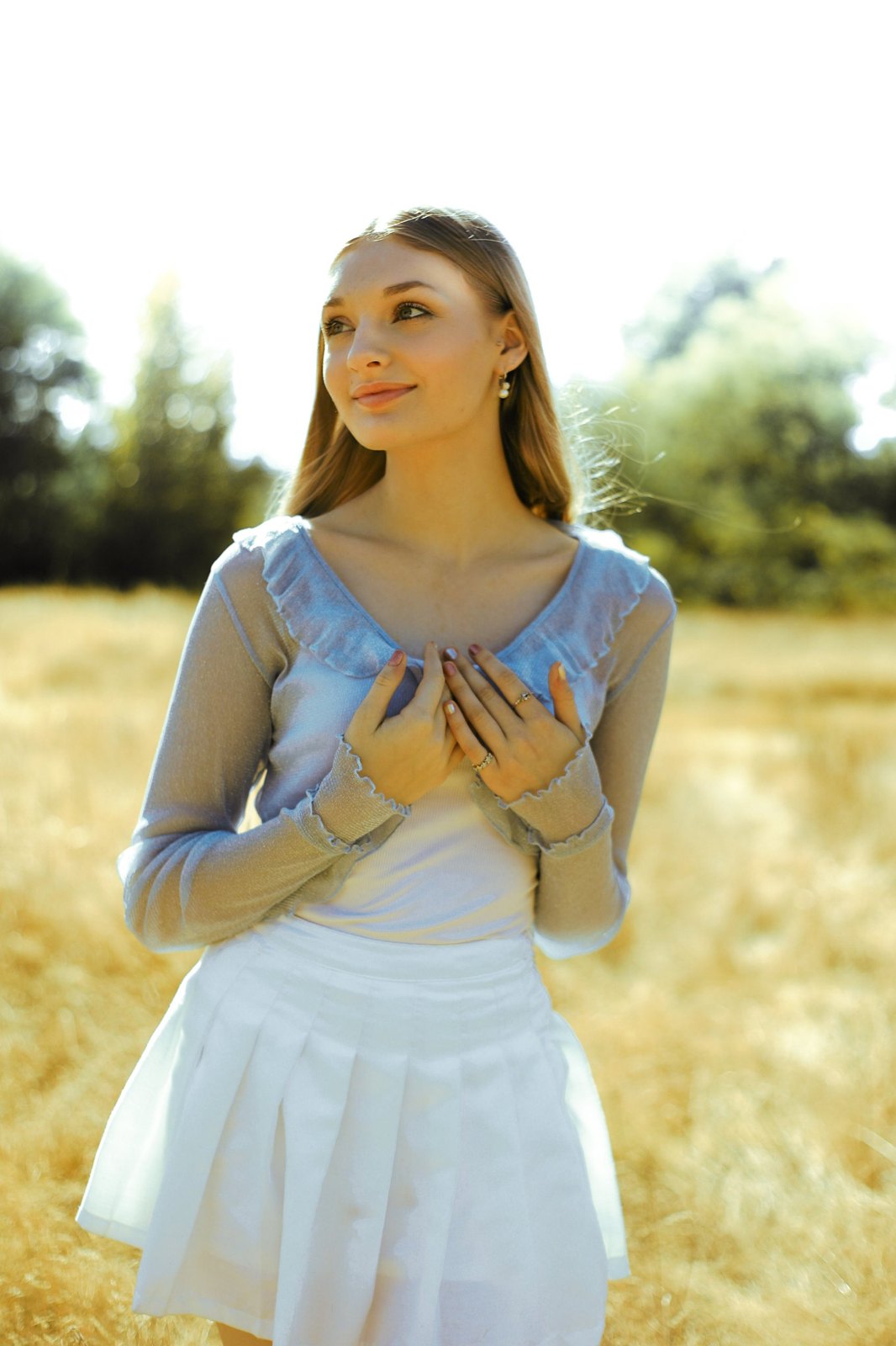 Senior with hands to her heart, looking into the summer light